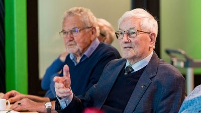 twee oudere mannen die aan tafel zitten
