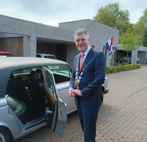 Burgemeester Hans Janssen bij auto voor lintjesregen