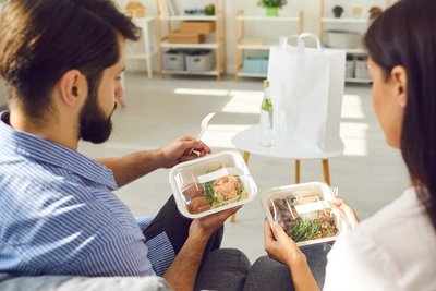 man en vrouw pakken hun afhaal eten uit 